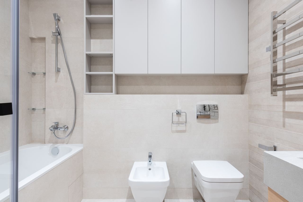 Interior of modern light bathroom with bidet and toilet next to sink and bath