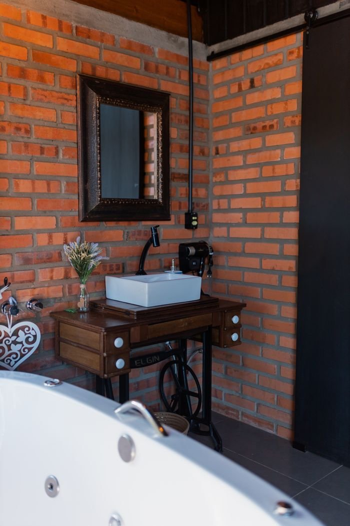 Cozy bathroom featuring a vintage vanity set against an exposed brick wall, creating a rustic ambiance.