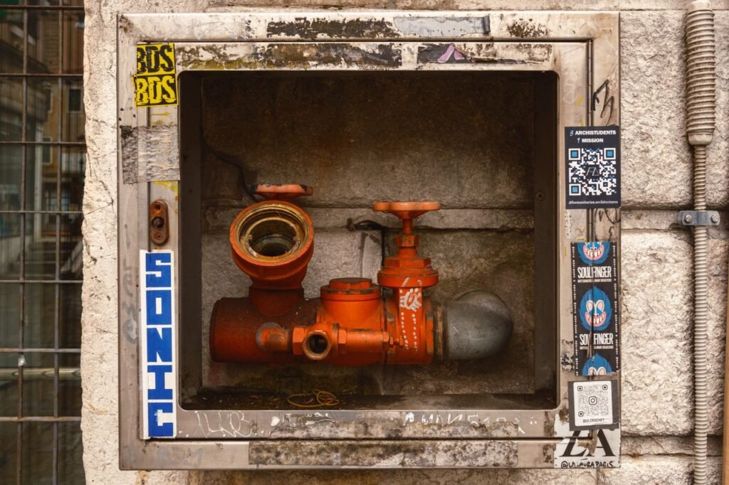 A detailed view of a rusty orange water valve enclosed in a metal frame, located in Venice, Italy.