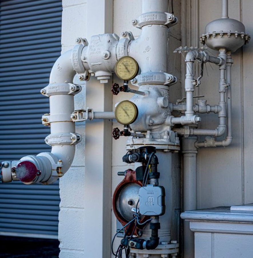 Close-up shot of an industrial pipe system featuring pressure gauges and valves outdoors.