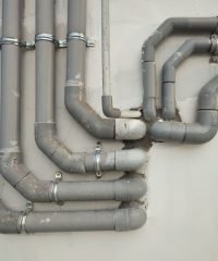 Close-up of interconnected gray metal pipes on an outdoor wall showcasing industrial design.
