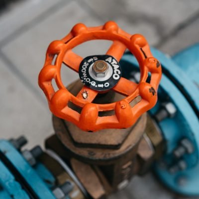 Close-up of orange valve on a blue pipeline, showcasing industrial equipment details.