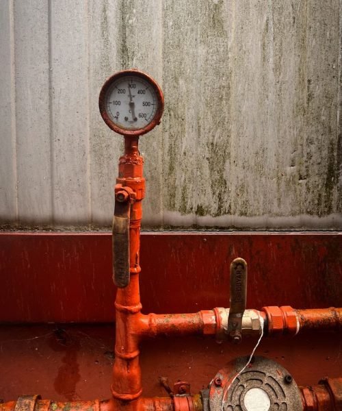 Close-up of a pressure gauge on industrial pipes, showcasing mechanical equipment and infrastructure.