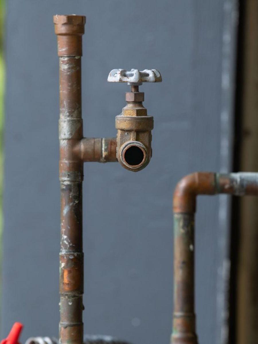 Detailed view of an old, rusty industrial water pipe with valve, conveying vintage industrial aesthetics.