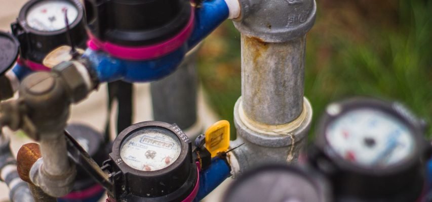 Detailed image of industrial water pressure gauges and pipes in an outdoor setting.