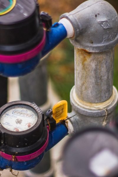Detailed image of industrial water pressure gauges and pipes in an outdoor setting.